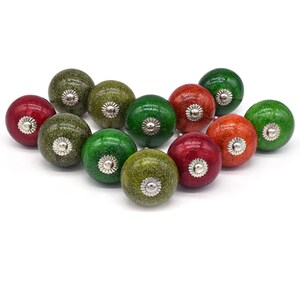 Peut inclure: Un ensemble de 12 boutons de porte en céramique de couleur verte, rouge et orange avec une finition argentée pailletée. Les boutons ont une base en métal argenté.