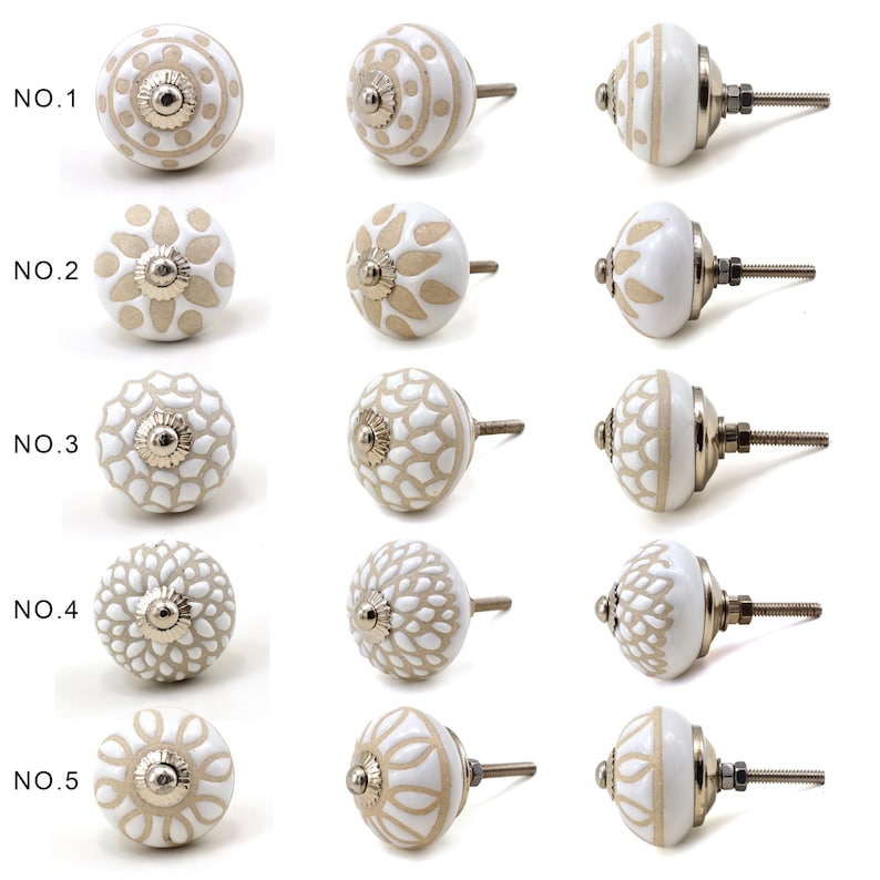 collection of white ceramic drawer knobs with intricate floral patterns and silver accents. The knobs are arranged in a basket lined with peach-colored fabric.