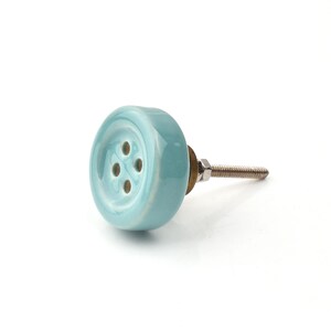 Hand-painted ceramic button knobs in cream, blue, turquoise; bold color cabinet hardware to match nursery decor.