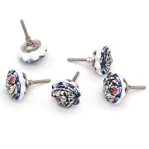 Könnte beinhalten: Fünf weiße Keramik-Schrankknöpfe mit floralen Mustern in Rot, Grün und Blau. Jeder Knopf hat eine silberfarbene Metallschraube und einen dekorativen Rand.