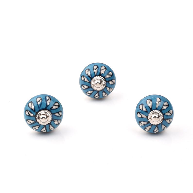Assorted hand-painted ceramic knobs in blue, black and white with mandala and floral motifs for cupboard handles and kitchen decor.
