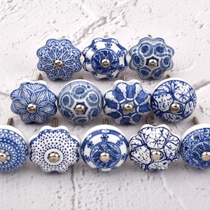 Könnte beinhalten: Zwölf blaue und weiße Keramikknöpfe mit komplizierten Designs. Die Knöpfe sind in einem Halbkreis auf weißem Hintergrund angeordnet.