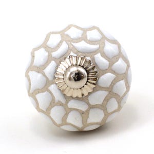 May include: White ceramic knob with a raised geometric pattern and a silver metal base.