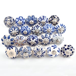 May include: A collection of 20 ceramic drawer knobs with blue and white floral patterns. The knobs are round and have a silver metal base.