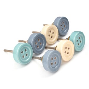 Hand-painted ceramic button knobs in cream, blue, turquoise; bold color cabinet hardware to match nursery decor.