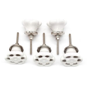 Puede incluir: Juego de seis pomos de armario de cerámica blanca con diseño floral y tallos de metal plateado.