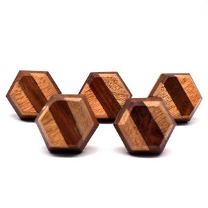 May include: Four hexagonal wooden knobs with a striped pattern in shades of brown. The knobs are made of wood with a natural finish.