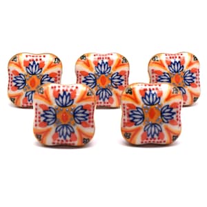 May include: Set of five ceramic cabinet knobs with a white background and a colorful floral pattern in shades of orange, blue, and red.