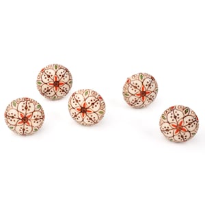 May include: Five decorative round beads with a floral design. The beads are off-white with a pattern of red, green, and brown accents. The floral design is centered with a red flower and surrounded by green leaves.