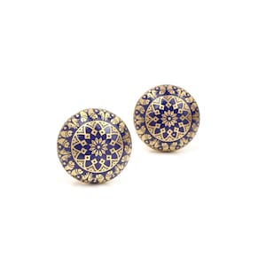 May include: Two round cabinet knobs with a navy blue and gold mandala design. The knobs have a gold border with a repeating pattern and a navy blue center with a detailed floral design. These decorative knobs are perfect for adding a touch of elegance to any furniture piece.
