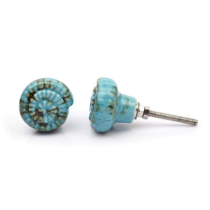 May include: A collection of twelve decorative cabinet knobs in various colours and patterns. Each knob features a round or oval shape with a metal bolt extending from the back. The designs include floral, geometric, and solid textures in shades of green, blue, orange, purple, white, and grey.
