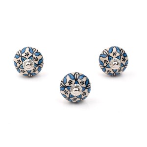 Assorted hand-painted ceramic knobs in blue, black and white with mandala and floral motifs for cupboard handles and kitchen decor.
