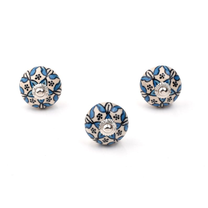 Assorted hand-painted ceramic knobs in blue, black and white with mandala and floral motifs for cupboard handles and kitchen decor.