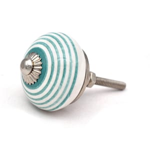 Könnte beinhalten: Weißer Keramik-Schrankknopf mit einem gestreiften Design in Tealblau und Weiß. Der Knopf hat eine silberne Metallbasis und eine Schraube.