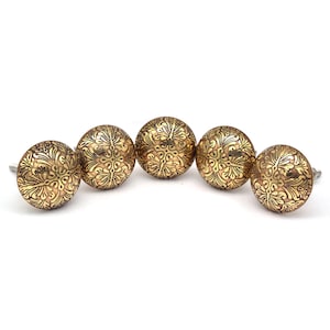 May include: Five gold-toned cabinet knobs with an ornate floral design.