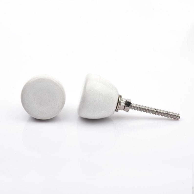 May include: A collection of twelve decorative cabinet knobs in various colours and patterns. Each knob features a round or oval shape with a metal bolt extending from the back. The designs include floral, geometric, and solid textures in shades of green, blue, orange, purple, white, and grey.