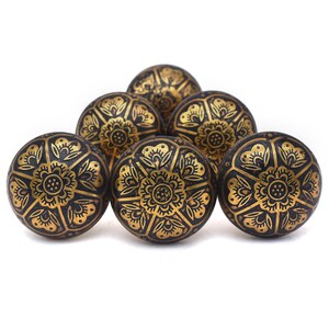 Etched brass flower cabinet knob with ornate gold pattern on dark background; decorative cabinet knobs for dresser hardware.
