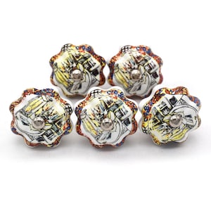 Puede incluir: Cinco tiradores decorativos de cerámica con diseño floral. Los tiradores tienen una base blanca con una ilustración colorida y un tornillo de metal plateado. La ilustración presenta detalles en amarillo, azul y rojo.