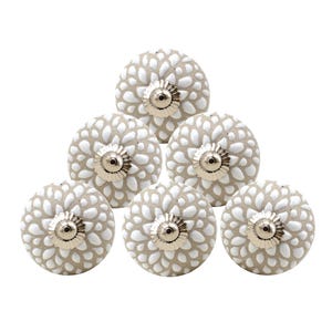 May include: Set of six white ceramic cabinet knobs with a beige background and a floral pattern. Each knob has a silver metal base.