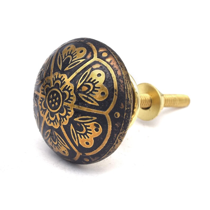 Etched brass flower cabinet knob with ornate gold pattern on dark background; decorative cabinet knobs for dresser hardware.