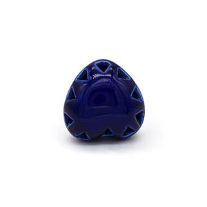 Puede incluir: Un adorno de cerámica en forma de corazón de color azul oscuro con un patrón geométrico de triángulos recortados.