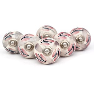 May include: Set of six ceramic drawer knobs with a white base and pink and gray floral pattern. Each knob has a silver metal accent in the center.