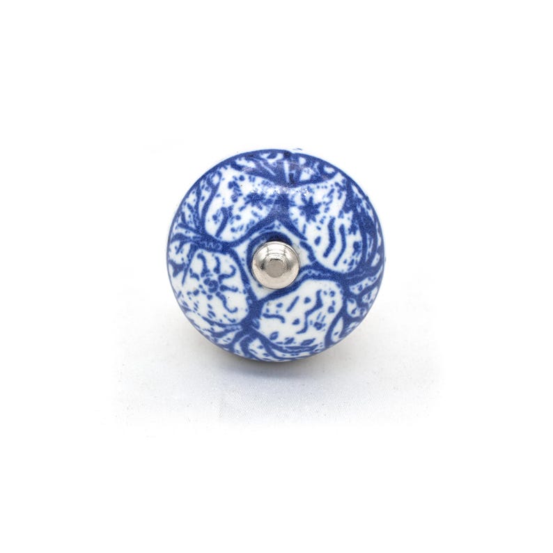 Pode incluir: Puxador de arm&aacute;rio redondo em cer&acirc;mica azul e branca com um design floral. O puxador tem um parafuso de metal prateado. Um elemento decorativo cl&aacute;ssico para m&oacute;veis.