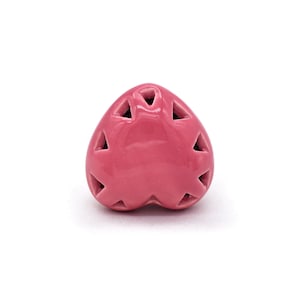 May include: A pink ceramic heart-shaped ornament with a decorative cut-out design. The ornament has a glossy finish and is perfect for adding a touch of charm to any space.