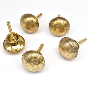 Peut inclure: Ensemble de cinq boutons de meuble en laiton. Les boutons ronds présentent un motif géométrique gravé. Un bouton est équipé d'une vis et d'une base. Couleur dorée chaude.
