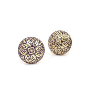 May include: Two decorative, spherical cabinet knobs. Each knob features a gold floral pattern on a dark blue background. The knobs are round and appear to be made of metal. The design is intricate and detailed.