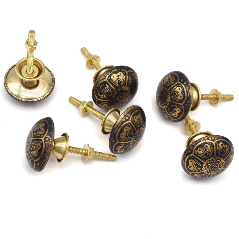 Etched brass flower cabinet knob with ornate gold pattern on dark background; decorative cabinet knobs for dresser hardware.