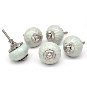 Peut inclure: Ensemble de cinq boutons de cabinet en céramique avec un glaçage vert clair et un motif floral blanc. Chaque bouton a une base en métal argenté.