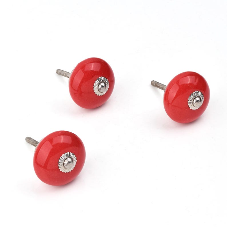 Red ceramic knobs with hand-painted white floral and mandala designs; assorted cabinet knobs for furniture and home décor.