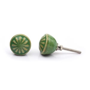 May include: A collection of twelve decorative cabinet knobs in various colours and patterns. Each knob features a round or oval shape with a metal bolt extending from the back. The designs include floral, geometric, and solid textures in shades of green, blue, orange, purple, white, and grey.