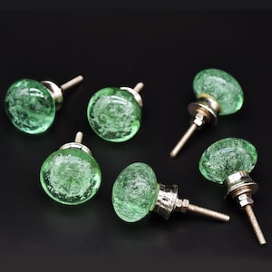 May include: Six green glass cabinet knobs with silver metal bases and screws. The knobs have a textured, bubbly appearance.