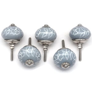 Grey ceramic knob with white hand-painted floral pattern; vintage shabby chic cabinet drawer pull with silver mounting stud.