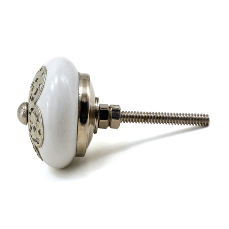 White ceramic cabinet knob with a silver flower motif and gold center; decorative furniture knob for cabinets and drawers.