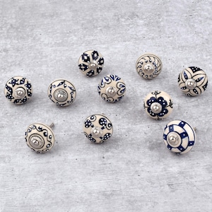 May include: Ten ceramic knobs with blue and white floral patterns. The knobs are round and have a silver screw in the centre.