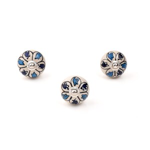 Assorted hand-painted ceramic knobs in blue, black and white with mandala and floral motifs for cupboard handles and kitchen decor.