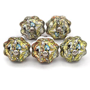 Puede incluir: Cinco pomos decorativos de cerámica para armarios con diseño floral. Los pomos presentan una combinación de colores amarillo, azul y blanco con un tornillo plateado. Los pomos tienen un aspecto artístico único.