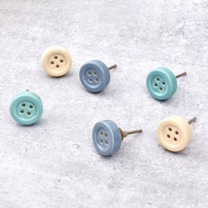 Hand-painted ceramic button knobs in cream, blue, turquoise; bold color cabinet hardware to match nursery decor.