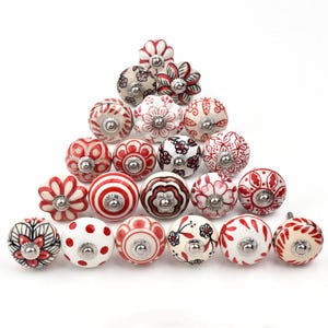 May include: Assortment of 18 ceramic drawer knobs with red and white floral patterns. The knobs have a silver metal base.