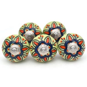 Può includere: Set di cinque pomelli per armadi in ceramica verde con un motivo floreale in tonalità di blu, rosso e nero.