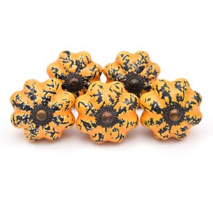 May include: Four ceramic cabinet knobs shaped like gourds with black and orange paint. The knobs have a rustic, farmhouse style.
