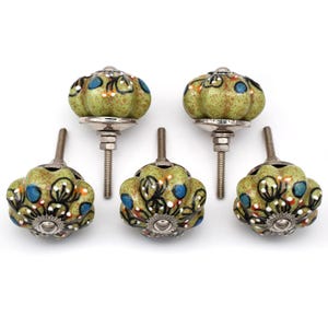 Puede incluir: Juego de seis pomos de armario de cerámica verde con diseño floral y tornillos de metal plateado. Los pomos tienen una superficie texturizada y están decorados con detalles blancos, azules y naranjas.