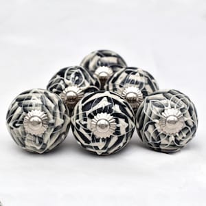May include: A set of six black and white ceramic cabinet knobs with a swirl pattern. Each knob has a silver metal base.