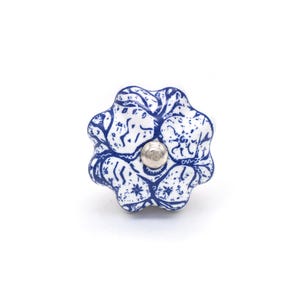 May include: A white and blue ceramic cabinet knob with a floral design. The knob has a silver metal screw and a rounded, flower-like shape. The blue pattern is a detailed, abstract design.