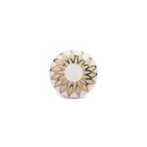 May include: A round ceramic cabinet knob featuring a white center surrounded by a stylized floral pattern. The design consists of alternating light mint green and metallic gold petals arranged in a circular sunburst motif on a white background.