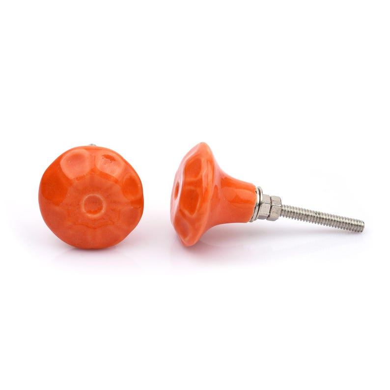 May include: A collection of twelve decorative cabinet knobs in various colours and patterns. Each knob features a round or oval shape with a metal bolt extending from the back. The designs include floral, geometric, and solid textures in shades of green, blue, orange, purple, white, and grey.