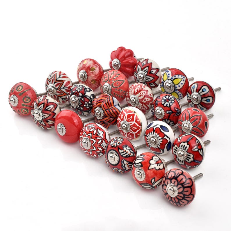 Red ceramic knobs with hand-painted white floral and mandala designs; assorted cabinet knobs for furniture and home décor.